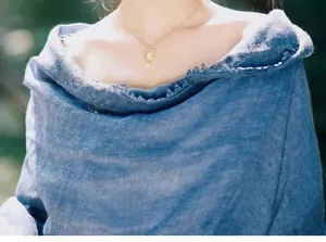 Gros plan d'un collier portrait doré avec perle sur vêtement en lin bleu dentelle