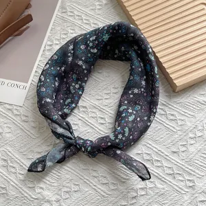 Detail eines Vintage-Seidenschals mit dunklem Paisley-Muster auf Strickhintergrund