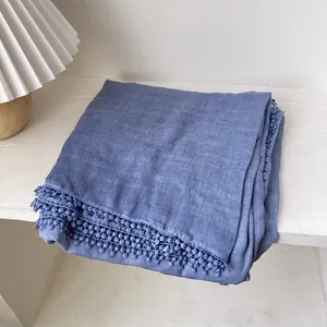 Détail d'une écharpe en coton bleu avec bordure en dentelle sur table blanche