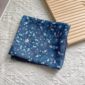 Detail eines dunkelblauen geblümten quadratischen Schals mit Paisleymuster auf weißer Struktur