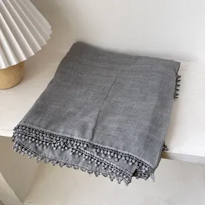 Détail d'une écharpe en coton et lin gris avec bordure ondulée perlée et texture