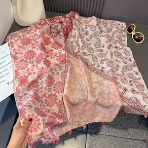 Pink paisley cotton linen scarf with red floral patterns and fringe on stone surface