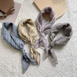 Elegante plissierte schmale Halstücher in Blau, Beige, Lila und Grau auf einem Tablett
