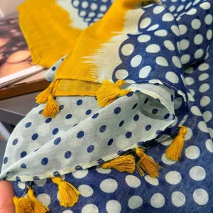 Détail d'une écharpe à pois bleus et jaunes avec pompons décoratifs et texture de tissu fin