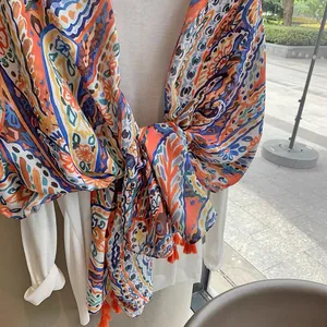 Close-up of bohemian paisley printed scarf with orange tassel fringe and vivid patterns