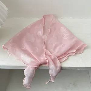 Rosa transparenter Seidenschal mit weißen Blumenstickereien für Damen auf Holzfläche