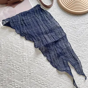 Détail d'un foulard en lin bleu marine à carreaux avec bords ondulés sur fond blanc