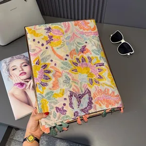 Détail de broderie florale et de franges à pompons colorés sur un châle en lin