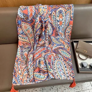 Close-up of bohemian paisley shawl with orange tassels and intricate fabric texture