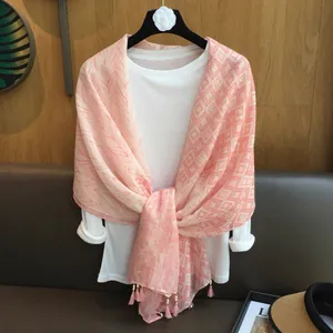 Gros plan d'une écharpe rose et blanche à glands avec motifs feuilles et géométriques