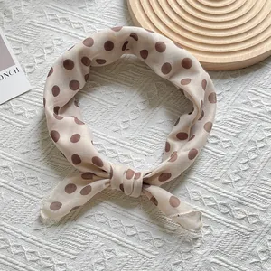Detail of soft beige silk scarf with brown polka dots tied in an elegant knot