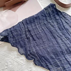 Détail du foulard triangle en lin bleu marine avec fin quadrillage doré et froissé