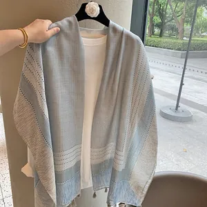Detail of light blue and grey checkered scarf with fringe and subtle polka dot patterns