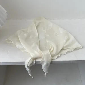 Detailaufnahme eines cremefarbenen Seidenschals mit Jacquardmuster und feiner Textur