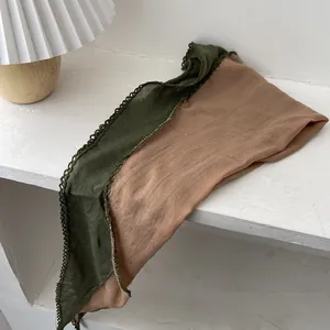 Détail d'une écharpe en coton et lin vert et beige avec bordure en dentelle au crochet