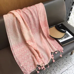 Gros plan sur un châle rose à motifs géométriques avec des pompons élégants