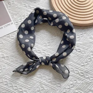 Close-up of a retro black silk scarf with white polka dots and delicate edge stitching