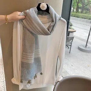 Light blue and white plaid scarf with tassels styled on a white long sleeve shirt