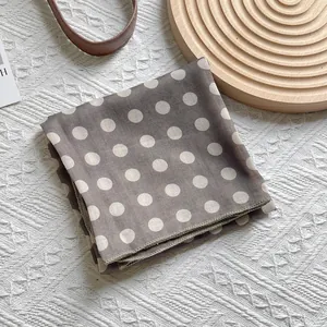 Close-up of a vintage gray silk scarf with white polka dots and finished hem edges