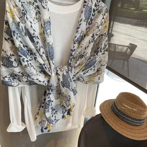 Detail of owl printed summer scarf with tassel edge on a white shirt background