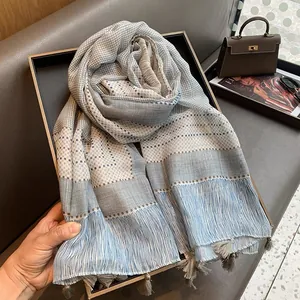 Detailed view of light blue checkered scarf with tassels on a luxury tray