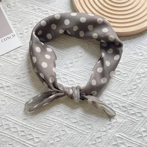 Close-up of retro taupe polka dot scarf tied in a bow on a textured woven surface