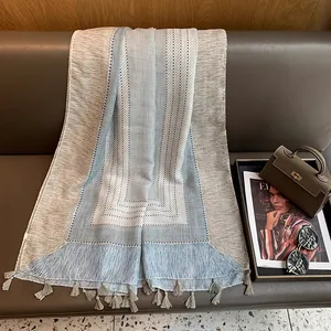 Detailed view of plaid linen scarf with elegant fringe on a stylish leather sofa