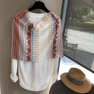 Detail of colorful geometric pattern scarf with bohemian tassels and white knit top