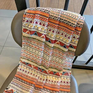 Detail of bohemian geometric pattern scarf with tassels on grey leather chair