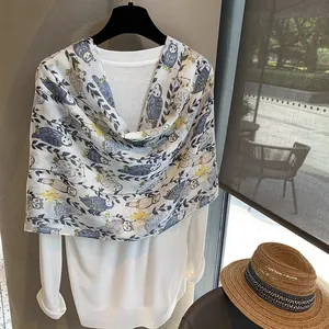 Detailed view of lightweight summer scarf with blue owl and floral prints on white base