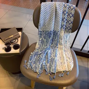 Détail d'une écharpe bleue à imprimé plumes avec perles et glands sur un fauteuil