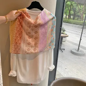 Detail of colorful floral print silk scarf with long tassels and lightweight fabric texture