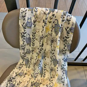 Detail of lightweight summer scarf featuring artistic owl and floral patterns on fabric