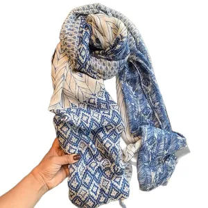 Écharpe bohème bleue et blanche avec motifs de plumes et glands sur fond blanc