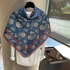 Detail eines dunkelblauen Paisley-Halstuchs mit burgunderrotem Rand auf Weiß