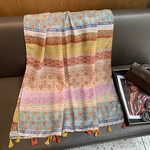 Detail of colorful printed summer scarf with tassels displayed on leather couch