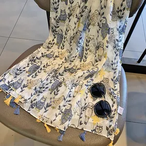 Detail of owl and leaf print on sheer scarf with colorful tassels on a leather chair