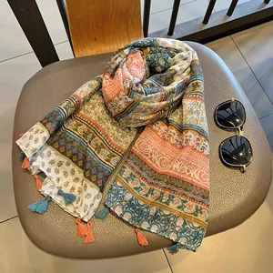 Close-up of Bohemian silk scarf with ethnic floral prints and colorful tassels on a chair