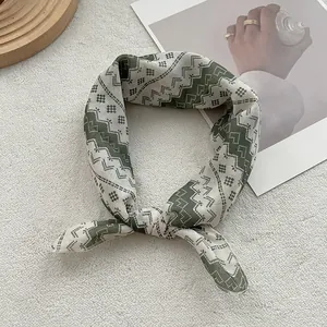 Green and cream silk square scarf with geometric wave patterns on white velvet