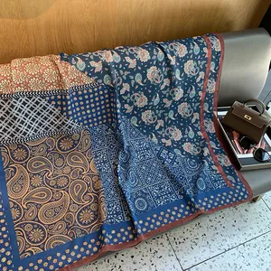 Detailaufnahme von blauem und rostfarbenem Paisley-Seidenschal auf einer Luxushandtasche