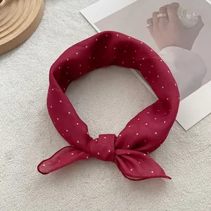 Close-up of a burgundy polka dot silk scarf with elegant bow design and soft texture