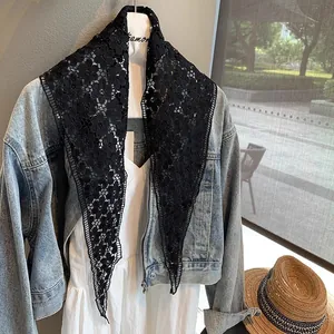 Elegant black hollow floral lace triangular shawl draped over denim jacket and white dress
