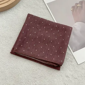 Detail of dark red silk scarf with white polka dots on soft textured background