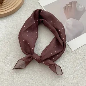 Close-up of knotted brown polka dot scarf on a textured background with elegant decor