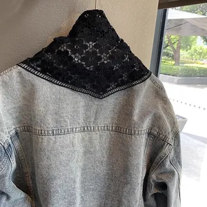 Detail showing black crochet floral lace shawl styled on a denim jacket collar