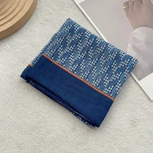 Dettaglio di un foulard di seta blu con motivo pied-de-poule e bordo arancione vivo
