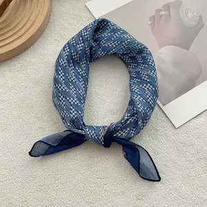 Dettaglio del foulard in seta blu con motivo pied de poule e bordi arrotolati