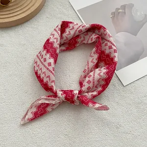 Detail of red and white geometric cotton scarf tied as a bow on a beige rug