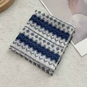 Detailed view of blue and white geometric cotton scarf on a soft textured background
