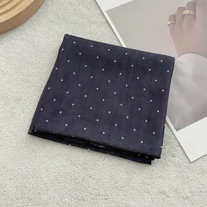 Detail view of navy blue polka dot silk scarf featuring neat hemmed edge and soft texture